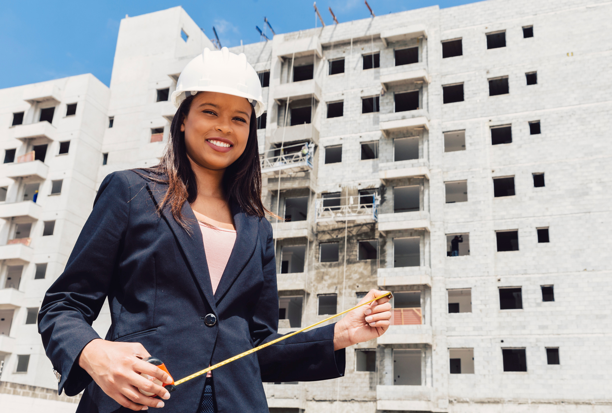 https://atriumhomes.ng/wp-content/uploads/2024/02/happy-african-american-lady-safety-helmet-with-measuring-tape-near-building-construction.jpg